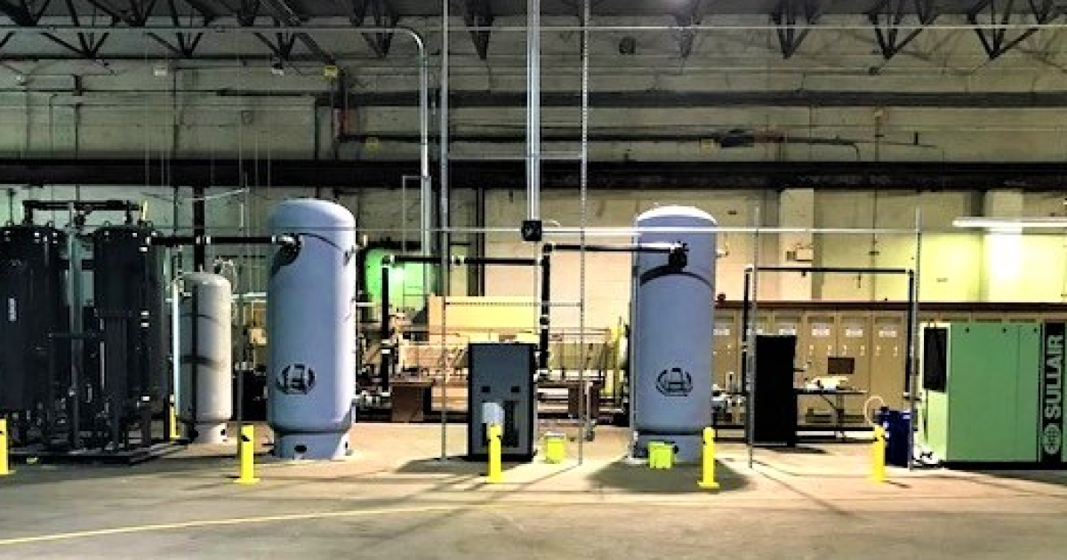 multiple in house nitrogen generation tanks in black and grey, a Sullair system in green, and yellow barrier poles on a facility floor