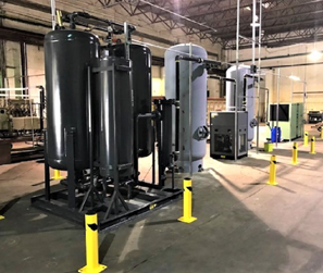 air compressors and nitrogen generation tanks on a facility floor with yellow safety poles
